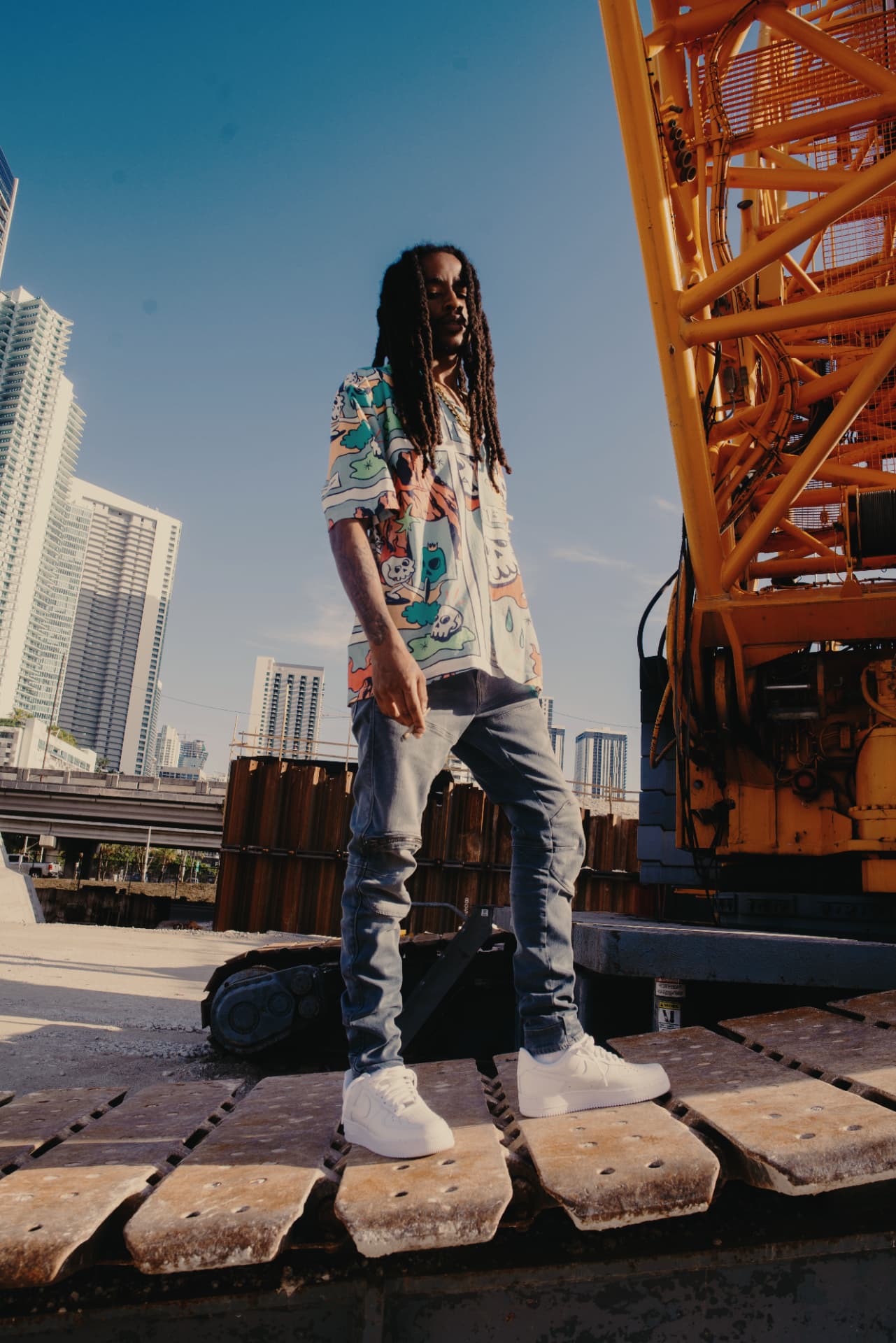 KJ Skippa Mak Marley standing on a Miami construction crane with the downtown skyline behind him